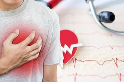 Man clutching his chest beside an EKG readout and a stethoscope.
