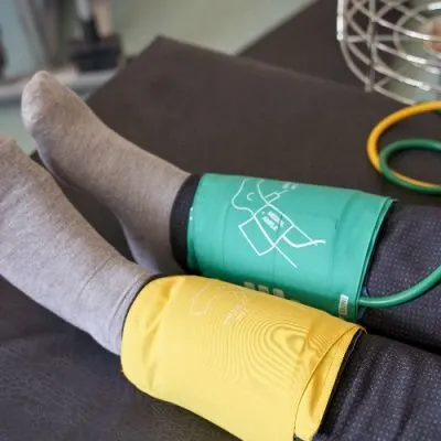 Green and yellow blood pressure cuffs wrapped around a person's ankles for an ABI test.