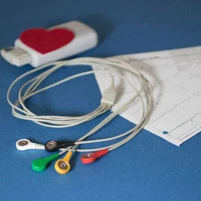 Colorful ECG leads and wires on a blue surface with heart rate tracings in the background.