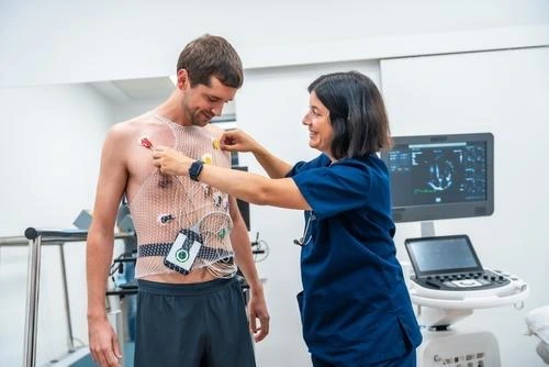 Medical professional attaching heart monitoring sensors to a male patient's chest.